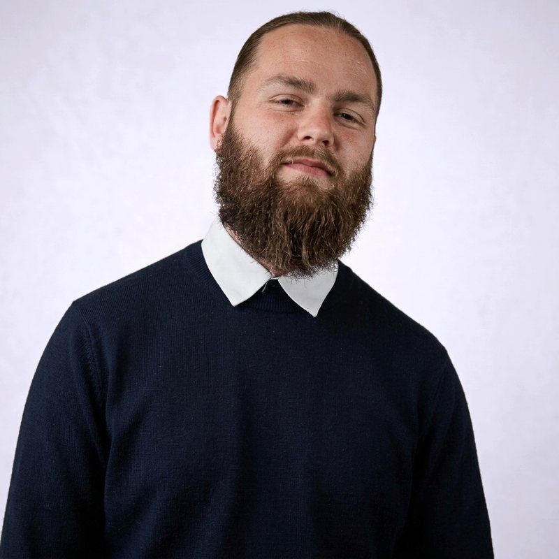 Portrait de Dorian Clowez, barbu, en pull marine sur un col de chemise blanc